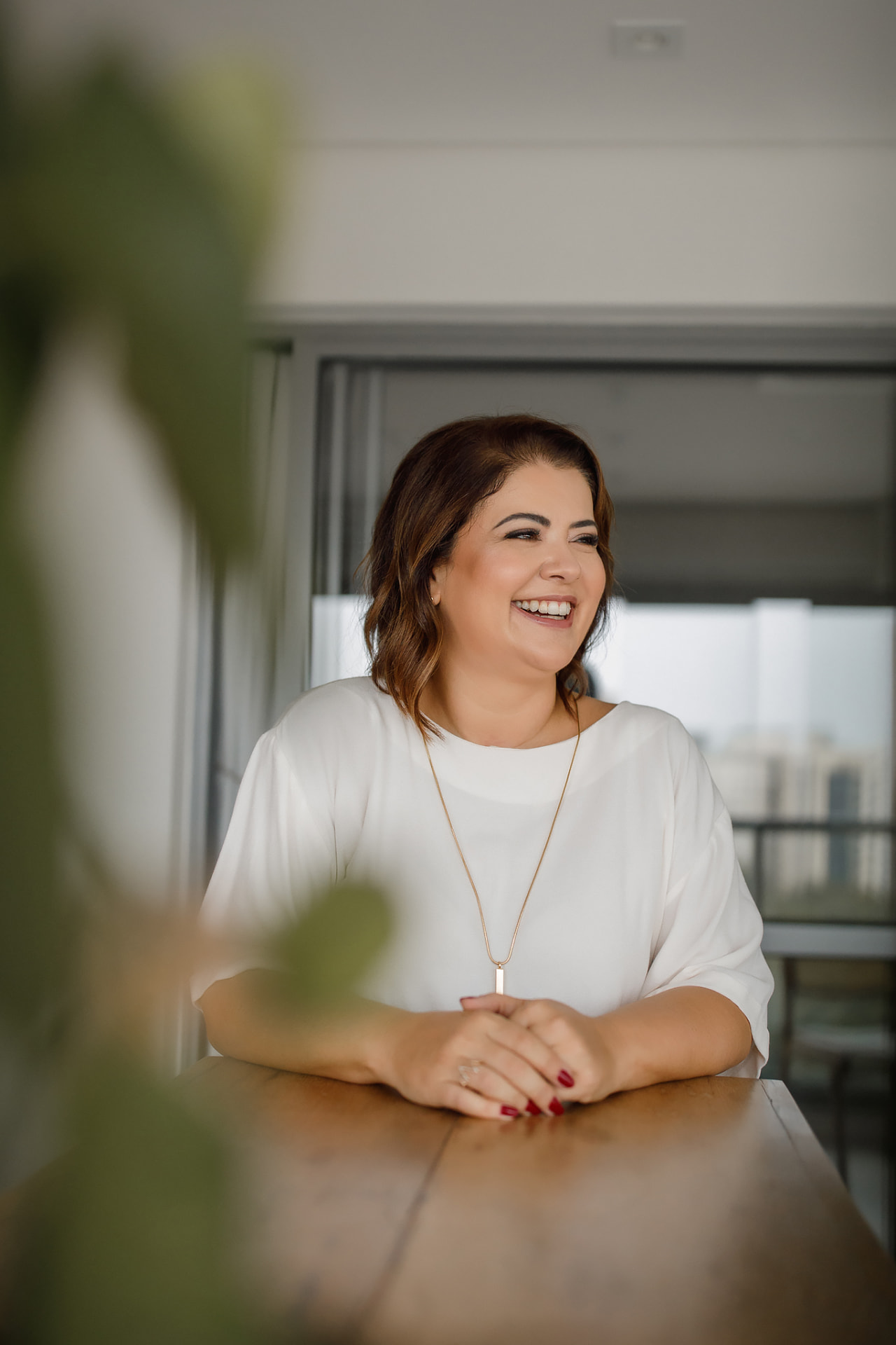 Rita Souza apoiada em uma mesa de madeira